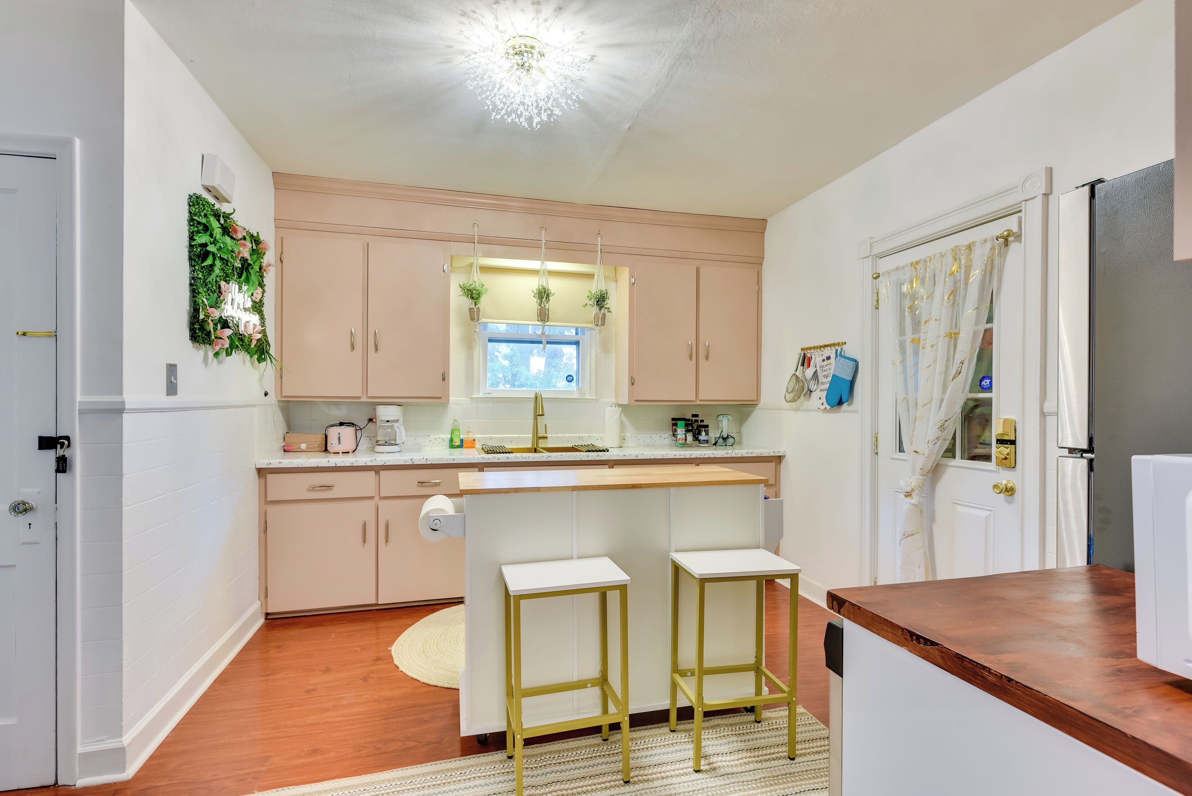 A compact kitchen with a central island, wooden cabinets, and a small refrigerator.