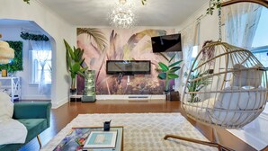 Ein Wohnzimmer mit großem Fernseher, einem Hängesessel und einer Wandmalerei.
