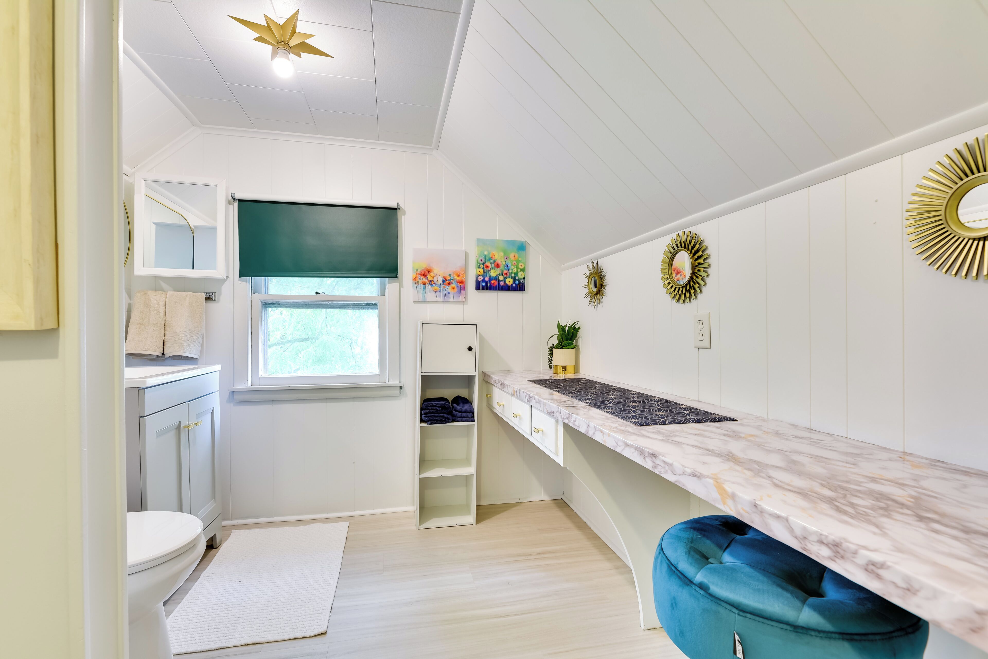 A compact kitchen with white cabinetry, a marble countertop, and a blue cushioned bench.