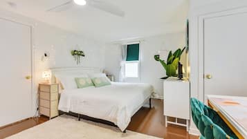 Une chambre à coucher avec un lit, une table de chevet, une lampe et un ventilateur de plafond.