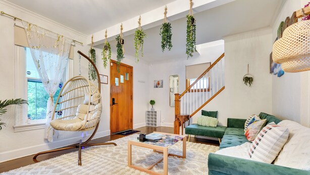 Ein gemütliches Wohnzimmer mit Hängesessel, einem grünen Sofa, einem Holztisch und einer Treppe, die in einen anderen Raum führt.