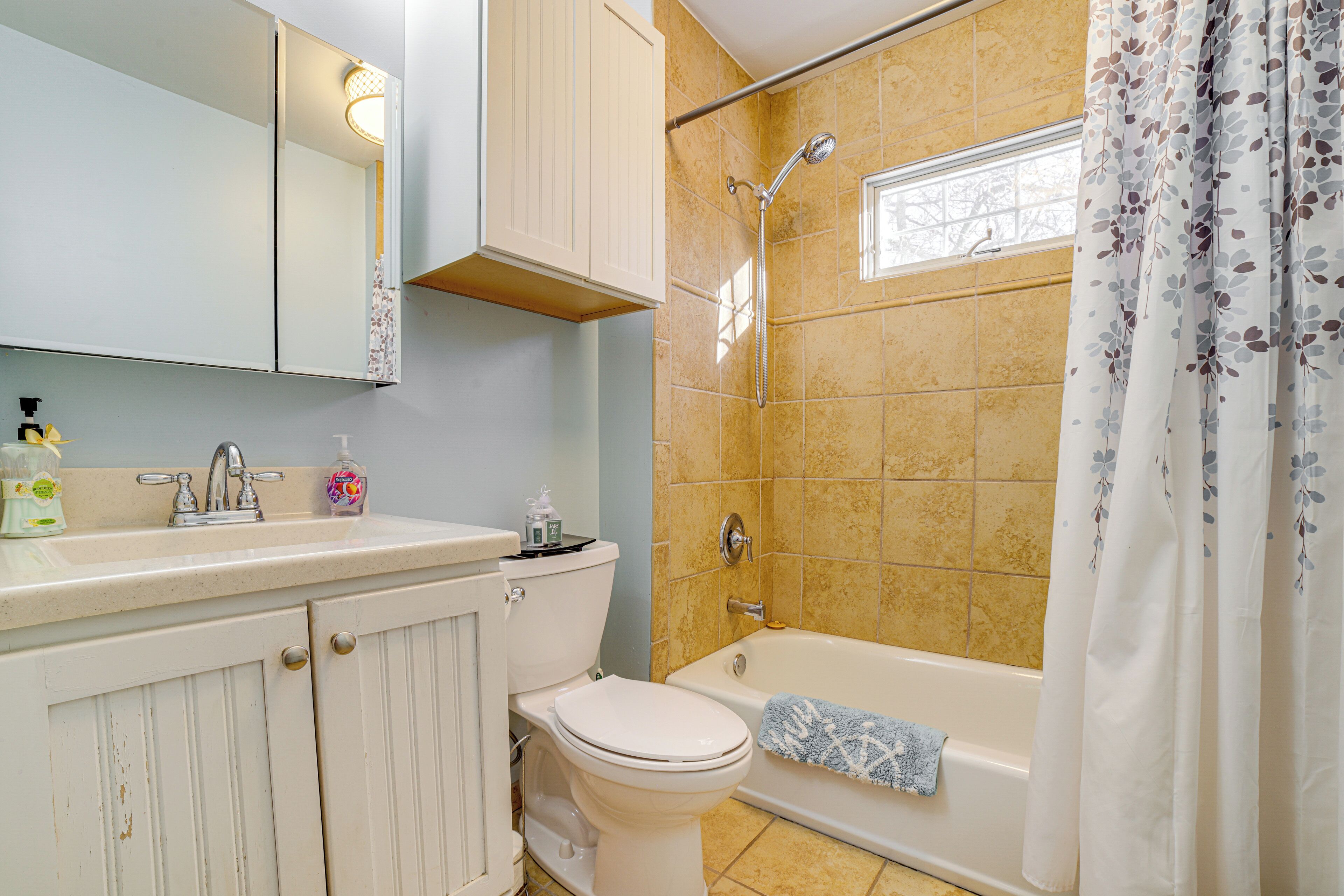 A bathroom with a toilet, sink, mirror, and shower.