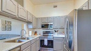 Una cocina moderna con electrodomésticos de acero inoxidable, armarios grises y piso de madera.