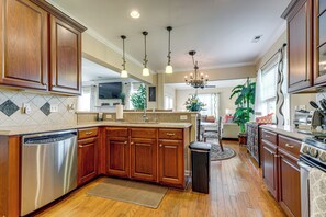 Una cucina con mobili in legno, lavastoviglie, piano cottura e lampadario.