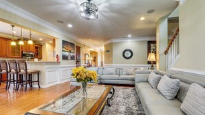 A spacious living room with a sofa, a coffee table, and a dining area with chairs and a kitchen in the background.
