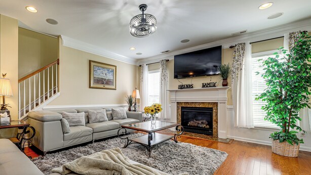 A living room with a sofa, coffee table, fireplace, TV, and staircase.
