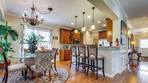 A spacious kitchen with wooden cabinets, a central island with bar stools, and pendant lighting.