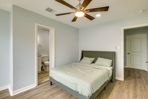 A bedroom with a bed, a ceiling fan, and a door leading to a bathroom. - Vacation Rental Home Near Lake Livingston! (Onalaska)