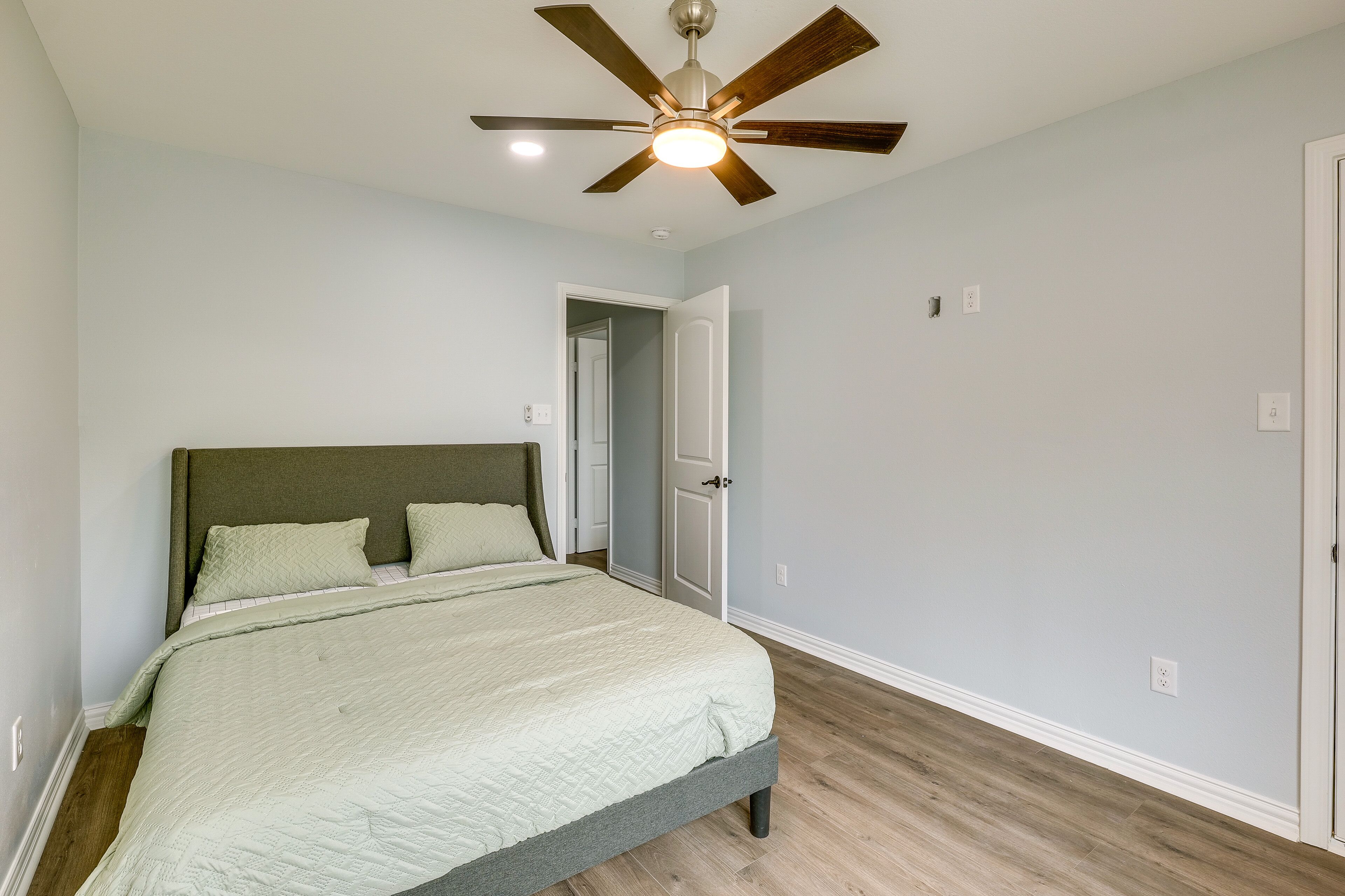 Ein Schlafzimmer mit einem Bett, einem Deckenventilator und einer Tür zu einem anderen Raum.