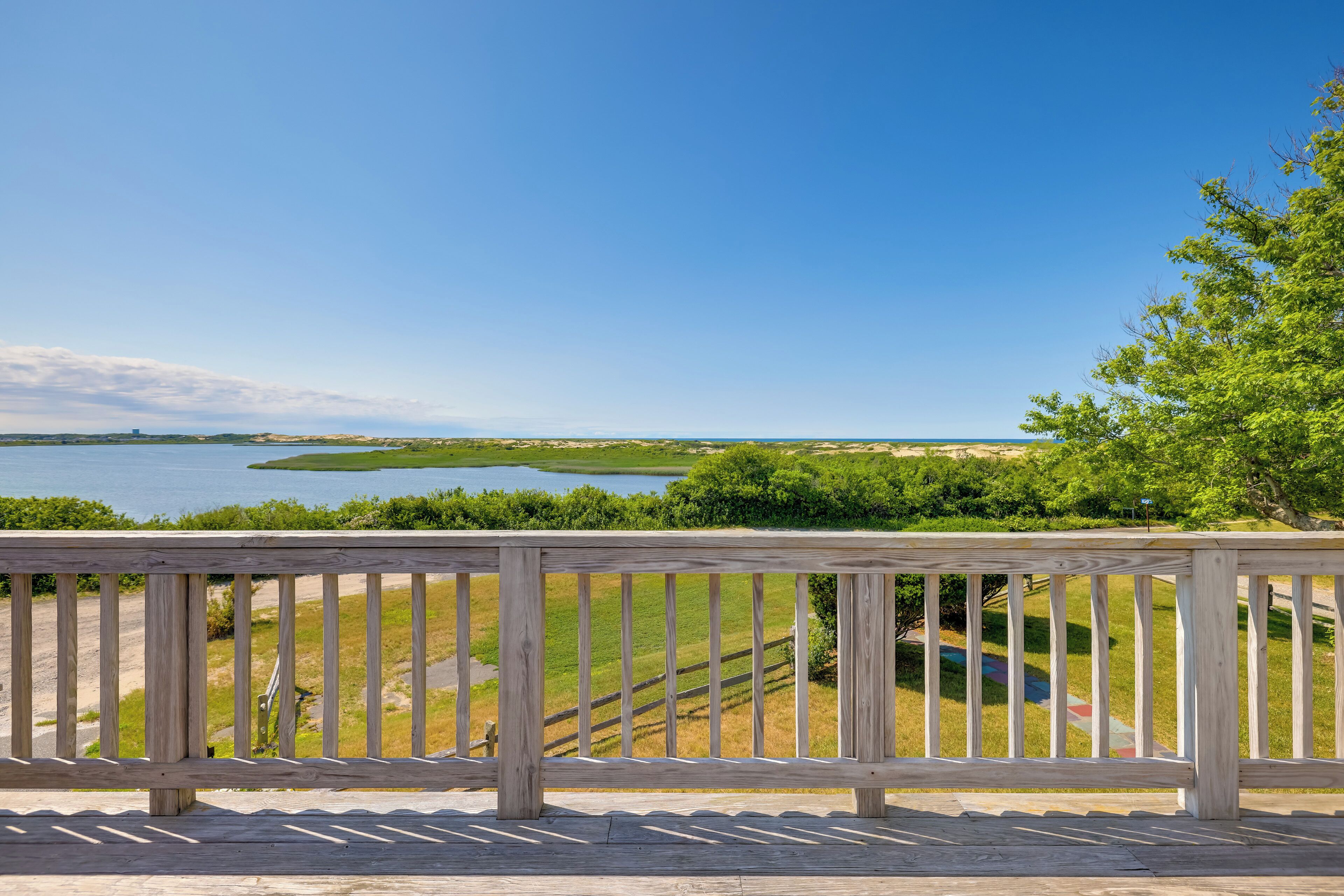 Terraza de madera con vista a un lago y terreno distante.