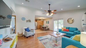 A spacious living room with a wooden floor, a ceiling fan, a teal sofa, and a dining area with wooden furniture. - Eufaula Oasis w/ Screened Porch: Unwind in Style! (Eufaula)