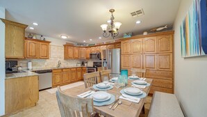 A kitchen with wooden cabinets, a dining table set for four, and a chandelier. - Eufaula Oasis w/ Screened Porch: Unwind in Style! (Eufaula)
