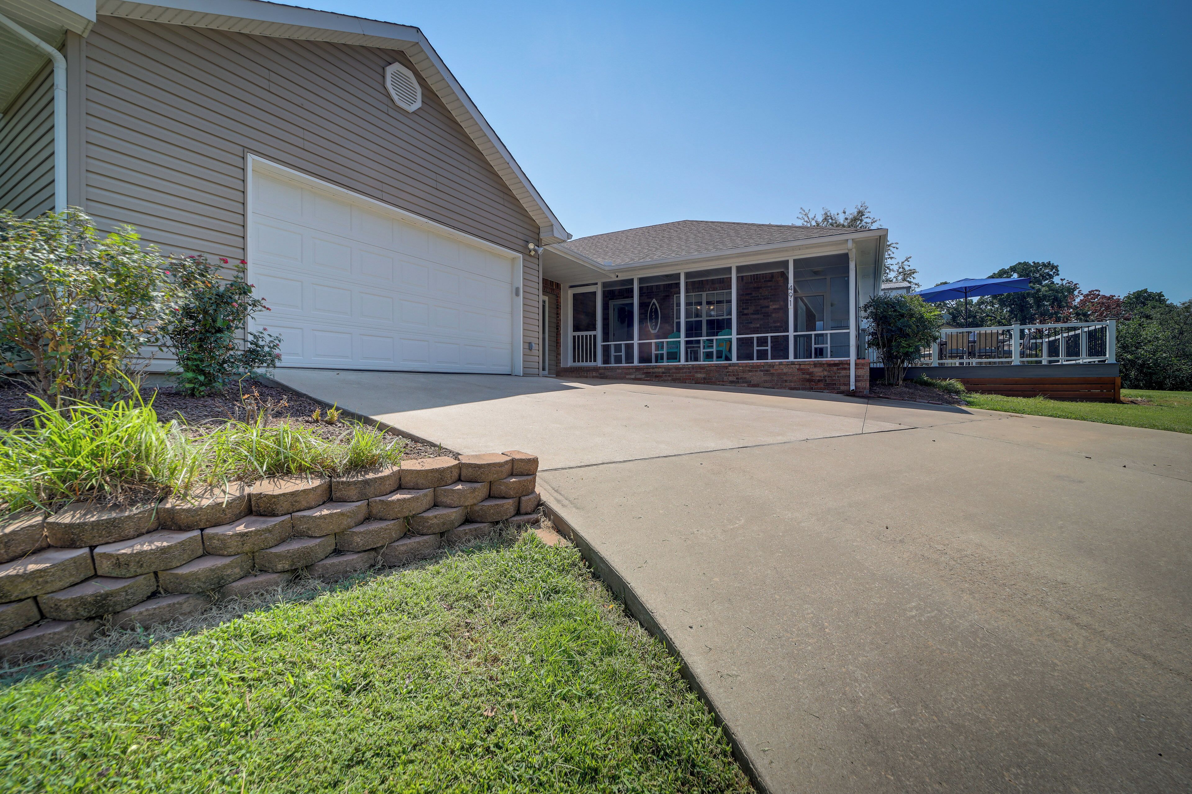A two-story house with a garage, a covered patio, and a well-maintained lawn.