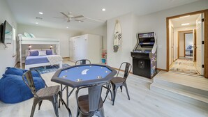 A room with a bunk bed, a pool table, bean bag chairs, a ceiling fan, and a surfboard on the wall. - Eufaula Oasis w/ Screened Porch: Unwind in Style! (Eufaula)
