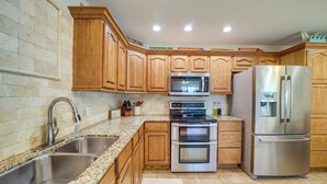 A kitchen with wooden cabinets, stainless steel appliances, granite countertops, and a double sink. - Eufaula Oasis w/ Screened Porch: Unwind in Style! (Eufaula)