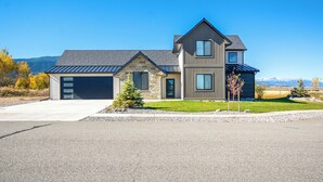 Une maison moderne à deux étages, dotée d’un garage, de fondations en pierre et d’un toit à pente.