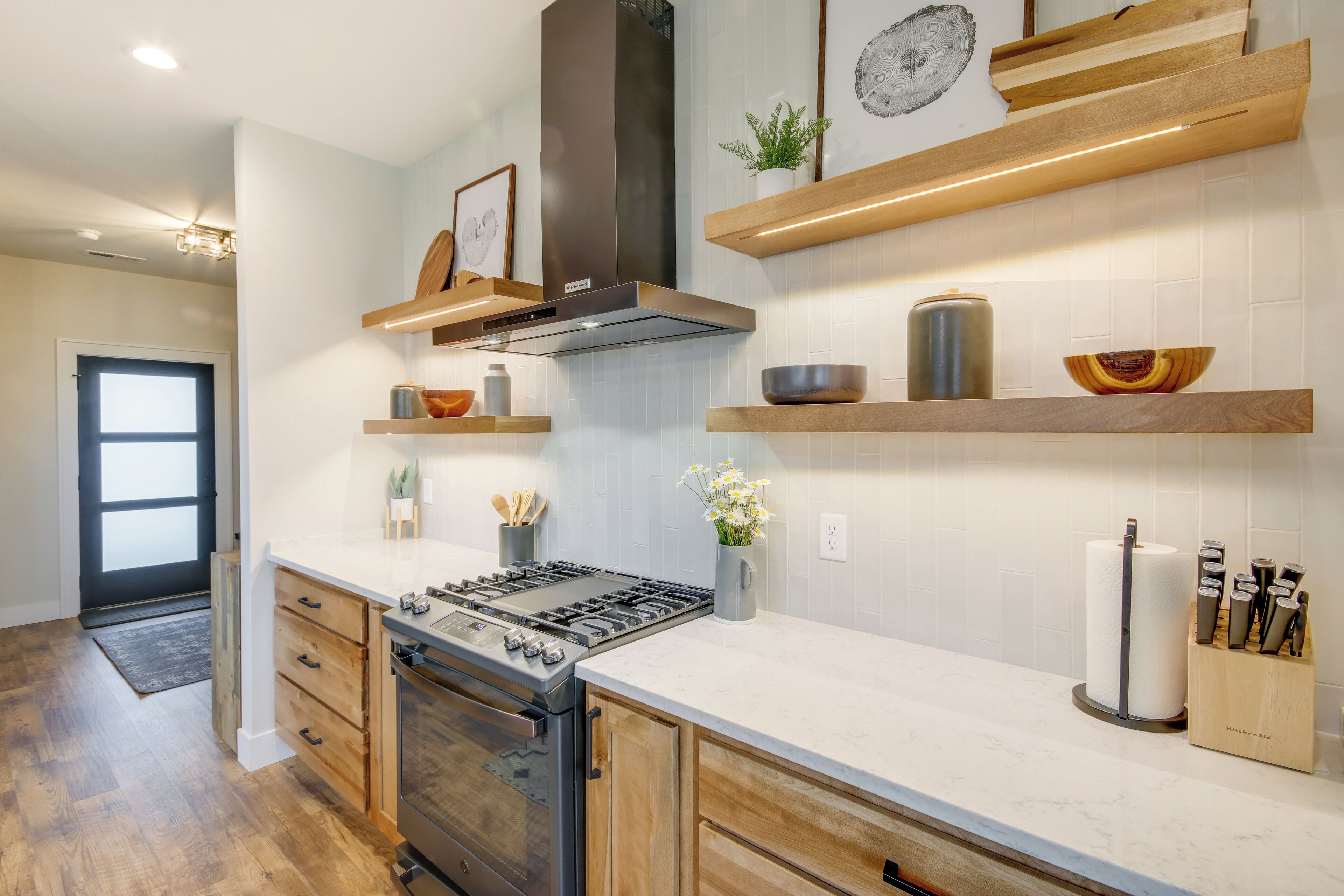 A modern kitchen with wooden cabinets, a stainless steel range, and a built-in oven.