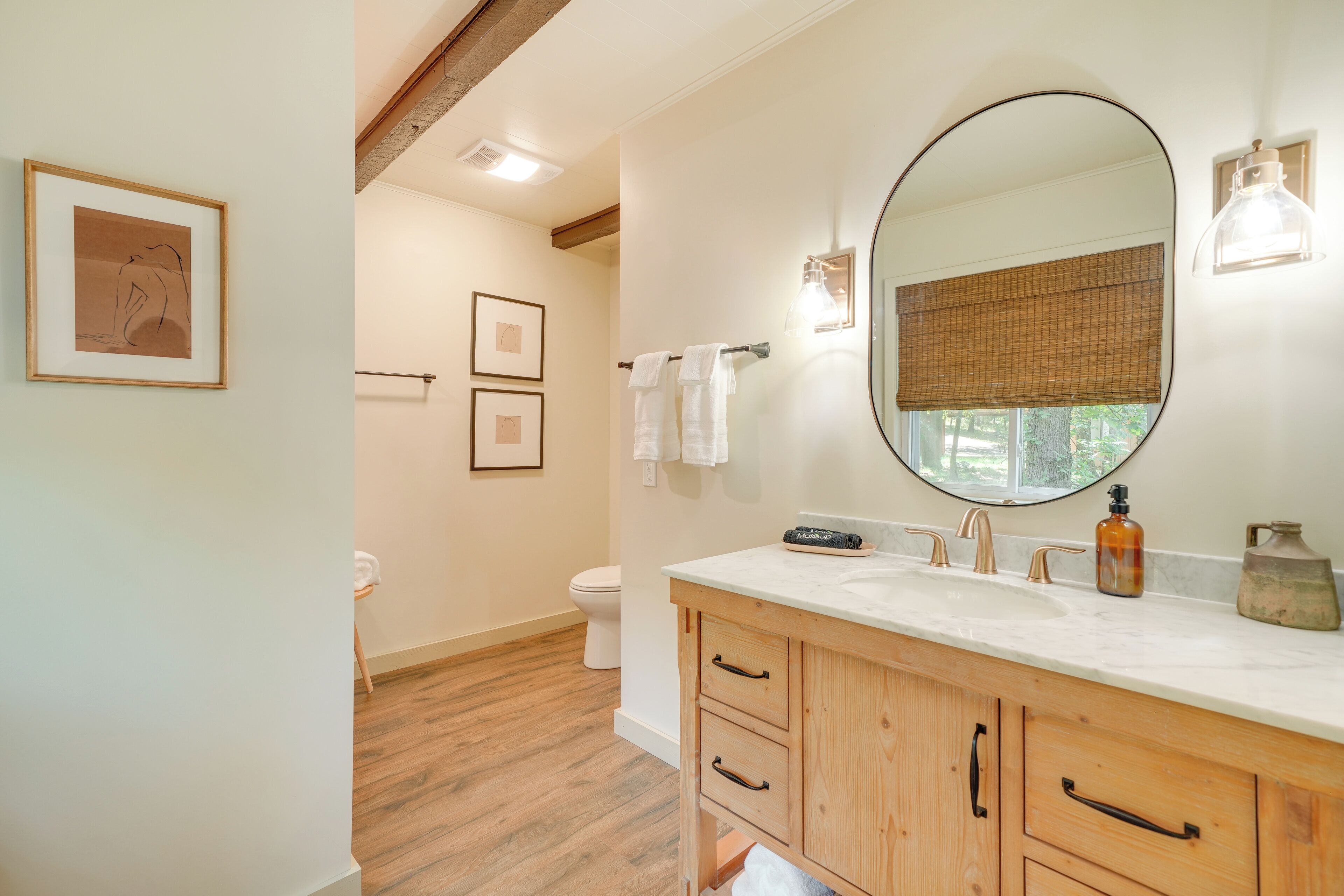 Une salle de bain avec un meuble-lavabo en bois, un grand miroir et des toilettes.