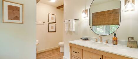 Une salle de bain avec un meuble-lavabo en bois, un grand miroir et des toilettes.