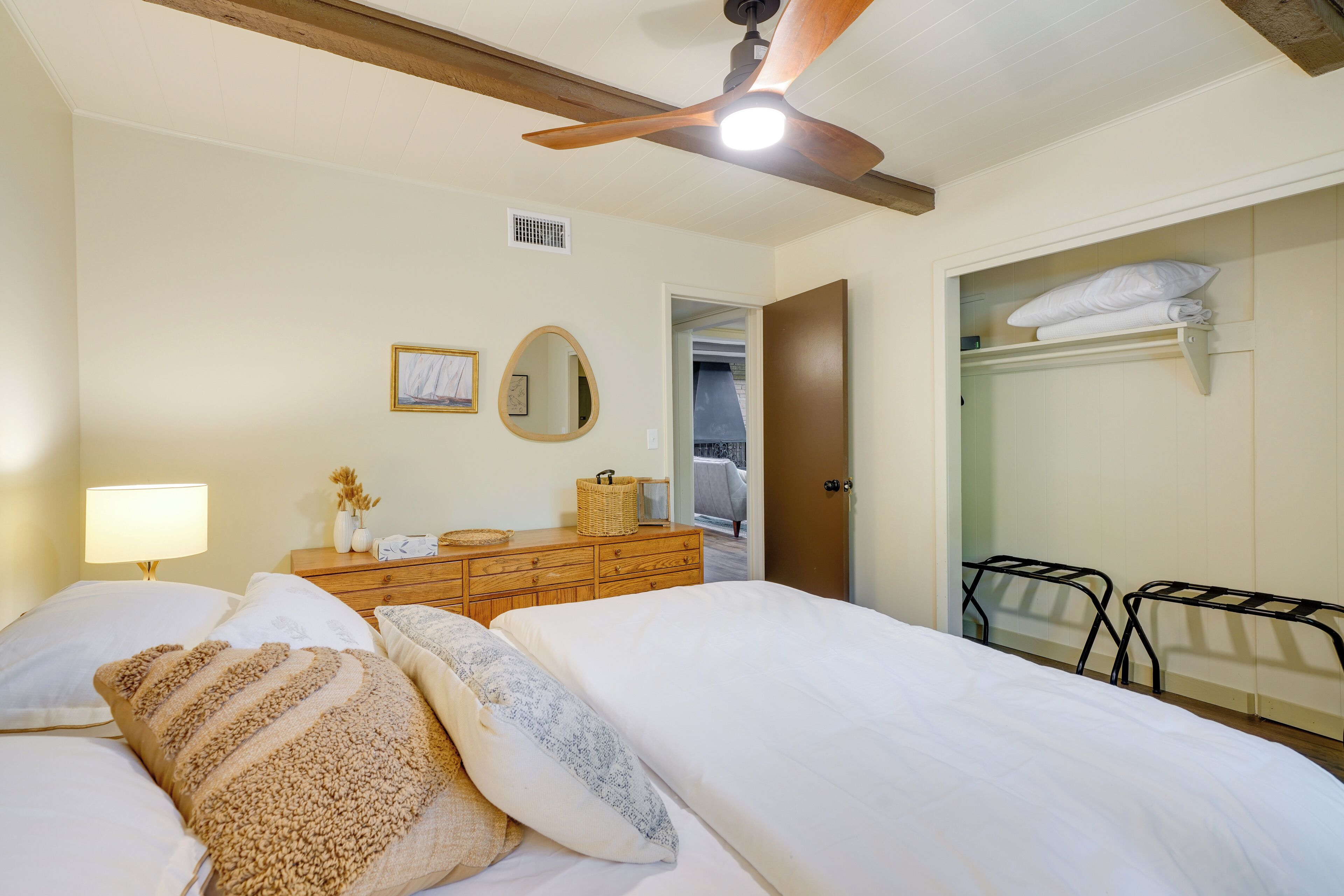 Een slaapkamer met een bed, een dressoir, een spiegel en een kast.