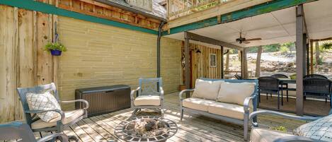 A wooden deck with outdoor furniture, a fire pit, and a covered area with chairs and tables.
