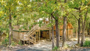 A wooden cabin with a staircase leading to a deck, surrounded by trees. - Idyllic Eufaula Vacation Rental: Close to Lake! (Eufaula)