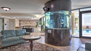 A lobby with a reception desk, a large aquarium, a sofa, and a patterned rug. - Dauphin Island Condo in Holiday Isle With Balcony! (Dauphin Island)