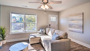 A living room with a sectional sofa, a ceiling fan, a large window, and a painting on the wall. - Greer Getaway w/ Smart TV ~ 1 Mi to Dtwn! (Greer)