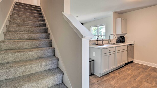 A staircase leading to a kitchen with white cabinets and a window. - Greer Getaway w/ Smart TV ~ 1 Mi to Dtwn! (Greer)
