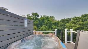 Un jacuzzi en una terraza al aire libre con barandilla de madera y un letrero.