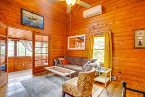 Cozy cabin with a comfortable seating area, sofa, chair, and small table, plus a ceiling fan and a personal touch from a framed picture.