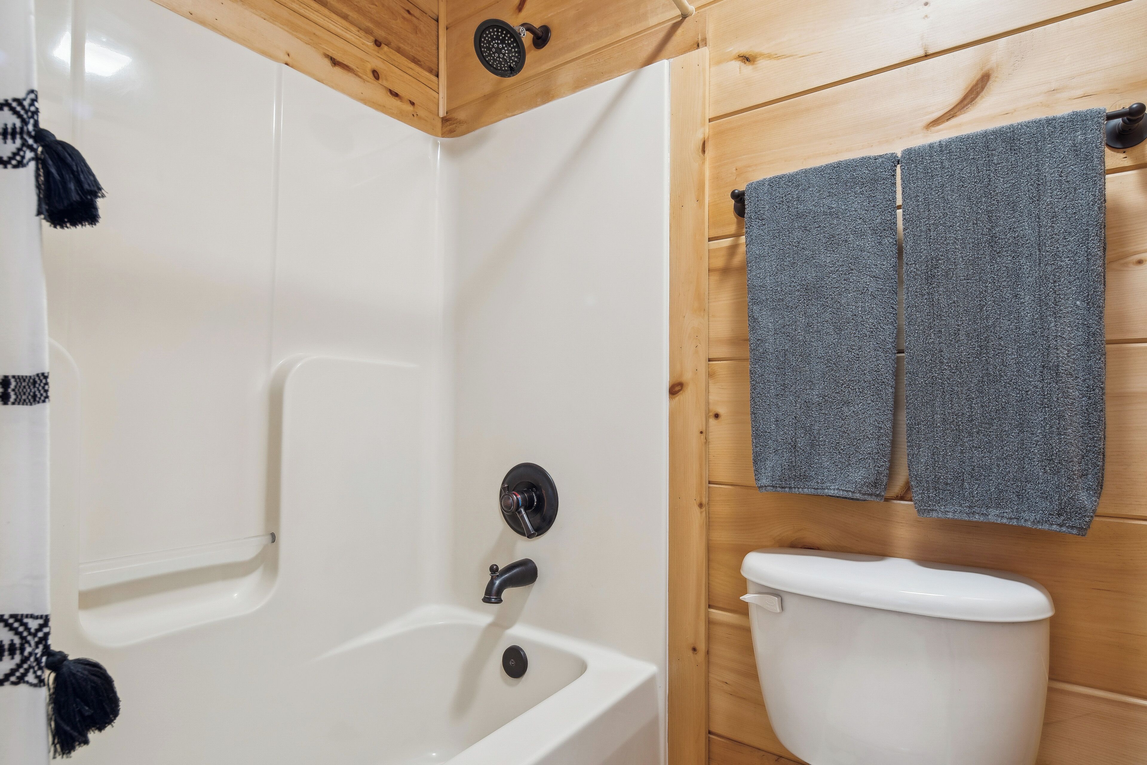 Un baño con bañera, inodoro y paredes de madera.