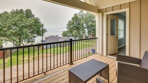 Un balcon abrité offrant une vue sur un quartier résidentiel, une terrasse en bois et du mobilier d’extérieur.