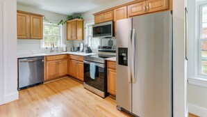 A kitchen with wooden cabinets, stainless steel appliances, and a window. - Chic Front Royal Retreat Near Shenandoah River! (Front Royal)