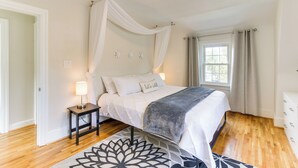 A bedroom with a canopy bed, bedside lamps, a patterned rug, and a window with curtains. - Chic Front Royal Retreat Near Shenandoah River! (Front Royal)