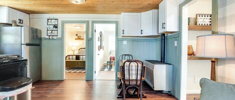 A modern kitchen with wooden flooring, white cabinets, and a dining area with a table and chairs.