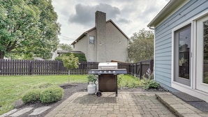 A backyard with a barbecue grill, a house, a wooden fence, and a paved patio. - Spacious Lewis Center Home w/ Yard & Gas Grill! (Lewis Center)