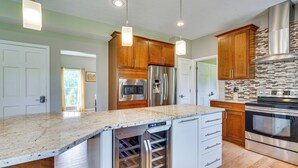 A modern kitchen with wooden cabinets, stainless steel appliances, and a built-in wine cooler. - Spacious Lewis Center Home w/ Yard & Gas Grill! (Lewis Center)