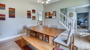 A dining area with a wooden table, benches, and chairs. There are abstract paintings on the walls. - Spacious Lewis Center Home w/ Yard & Gas Grill! (Lewis Center)