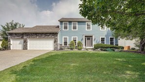 A two-story house with a garage, a well-maintained lawn, and a tree in the front yard. - Spacious Lewis Center Home w/ Yard & Gas Grill! (Lewis Center)