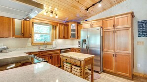 A modern kitchen with wooden cabinets, a stainless steel refrigerator, and a granite countertop. - Waterfront Eagle River Home w/ Dock + Fire Pit! (Eagle River)