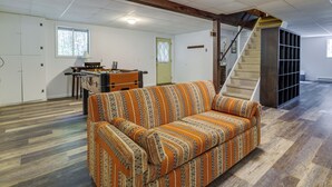 Tilava olohuone, jossa on kuviollinen sohva, ruokailutila ja portaat, jotka johtavat ylemmälle tasolle.