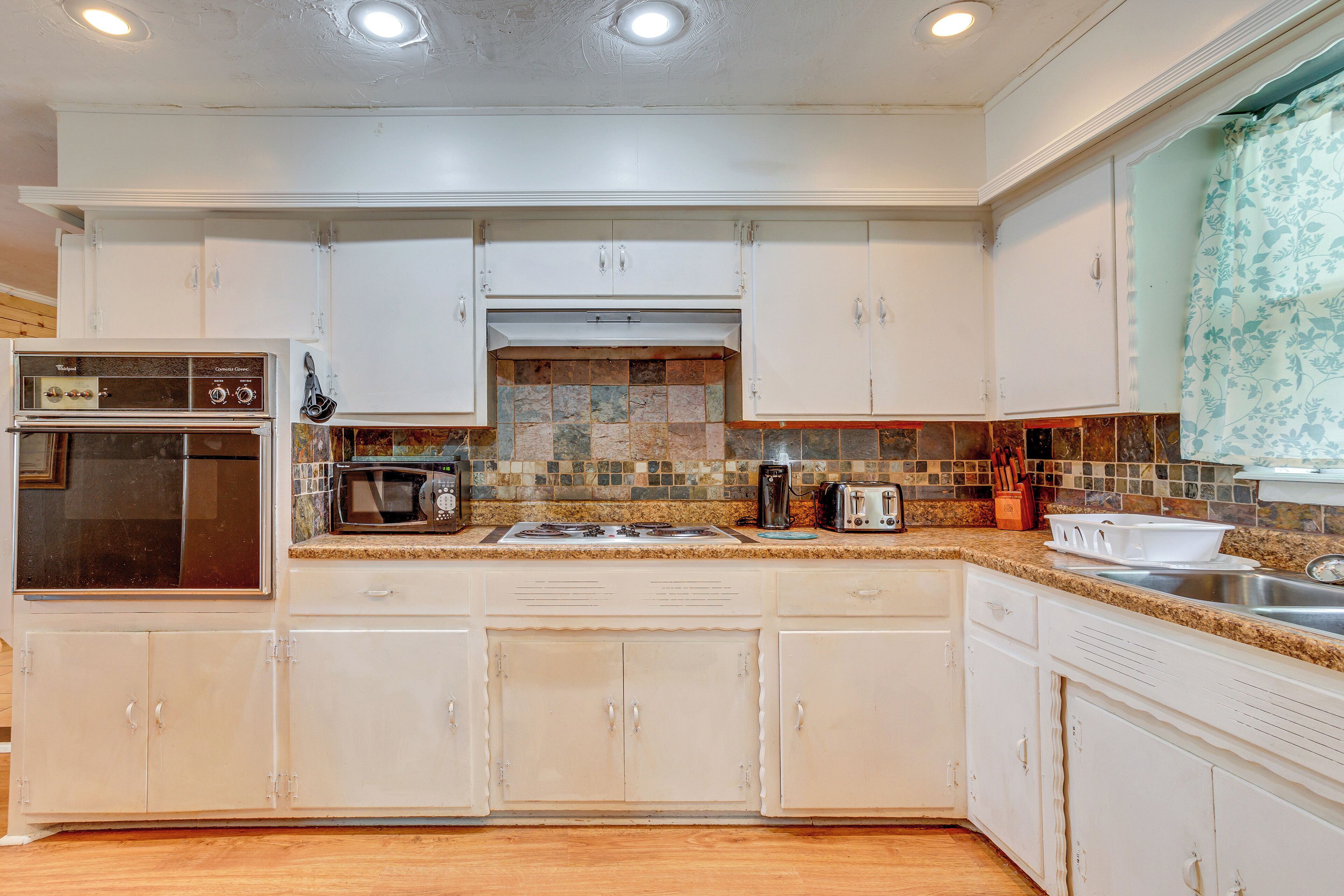 A kitchen with white cabinets, a tiled backsplash, and a built-in oven.