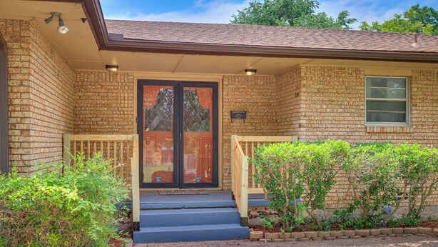 A brick house with a front door, a small porch, and a window.