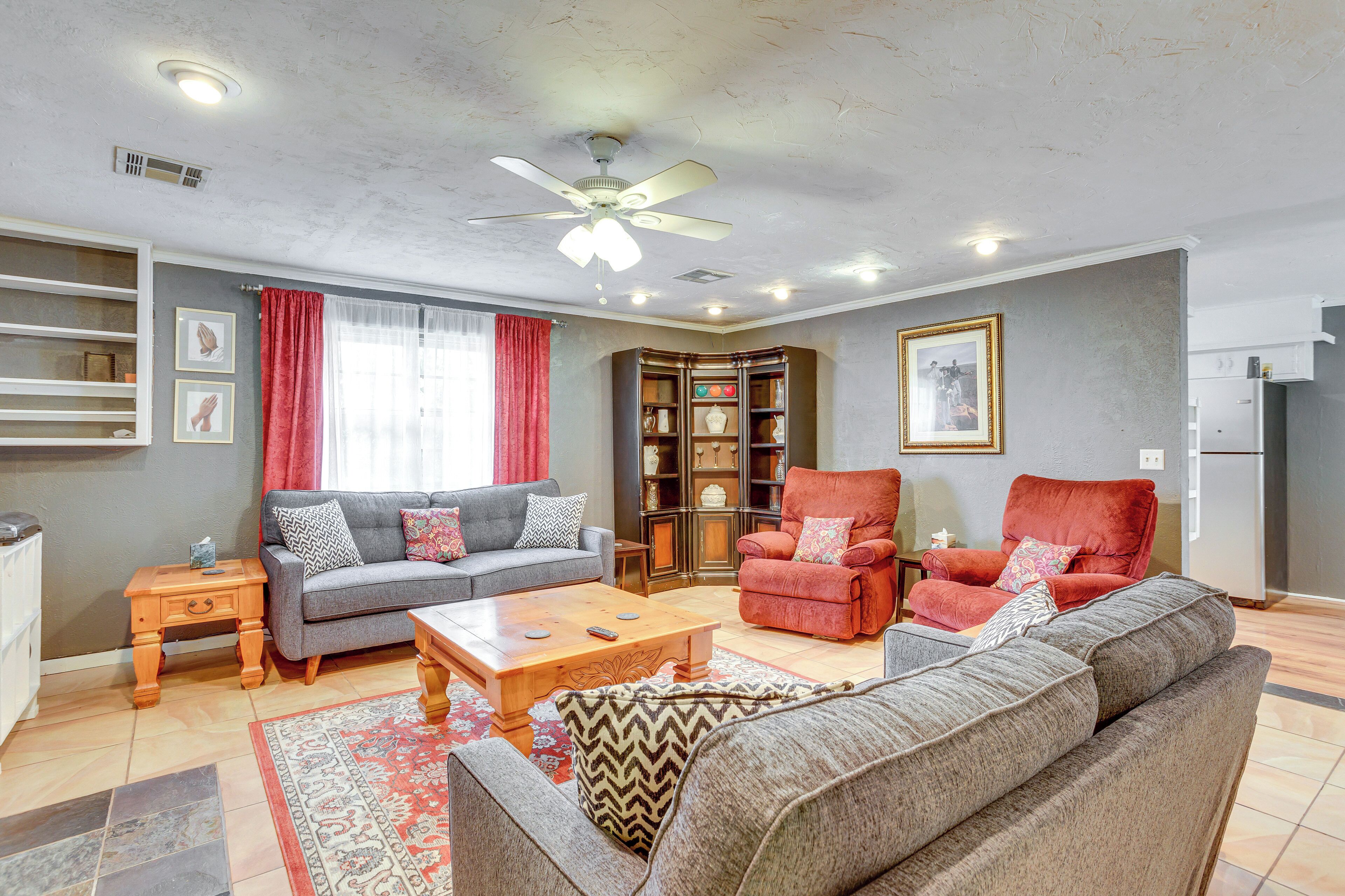 A living room with a grey sofa, a red armchair, a wooden coffee table, and a bookshelf.