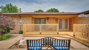 A brick house with a wooden deck, a bench, and a covered patio area.