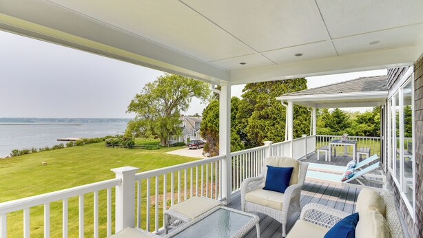 A covered porch with outdoor furniture, a view of the water, and a lawn. - Waterfront Massachusetts Vacation Rental w/ Deck (Westport Point)