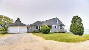 A two-story house with a garage, a covered porch, and a lawn. - Waterfront Massachusetts Vacation Rental w/ Deck (Westport Point)