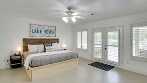 A bedroom with a bed, nightstands, a ceiling fan, a sign above the bed, and a view through the door. - Lakefront Hot Springs Condo w/ Dock Access & Views (Hot Springs)