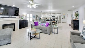 A spacious living area with a sofa, coffee table, and a television. A kitchen is visible in the background. - Lakefront Hot Springs Condo w/ Dock Access & Views (Hot Springs)